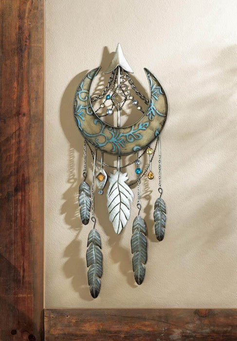 Crescent moon with feathers wall art, hanging against a tan wall.