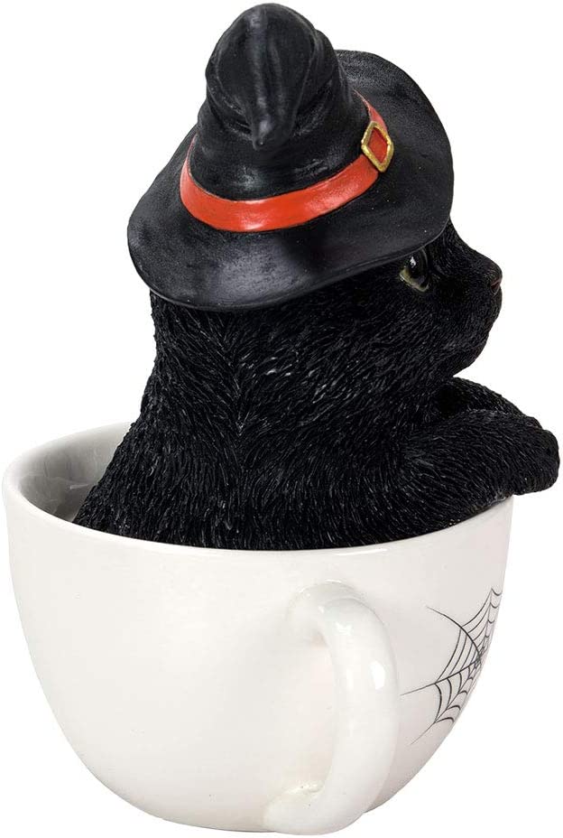 Black kitten in a white teacup. Cat wears a witch hat. Side view