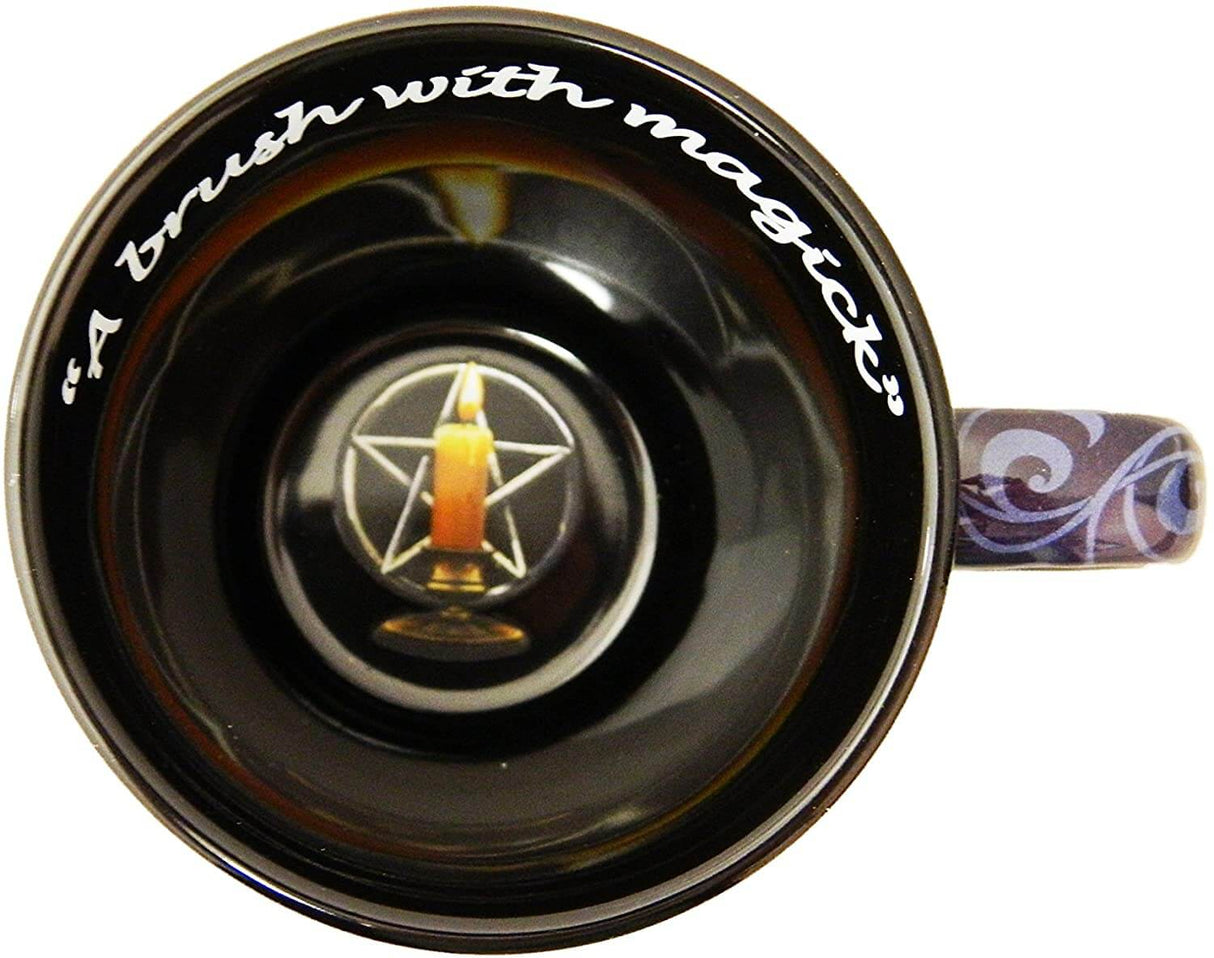 Inside of mug. Black with white text, "A brush with magick" and at the bottom is a pentacle with a burning candle