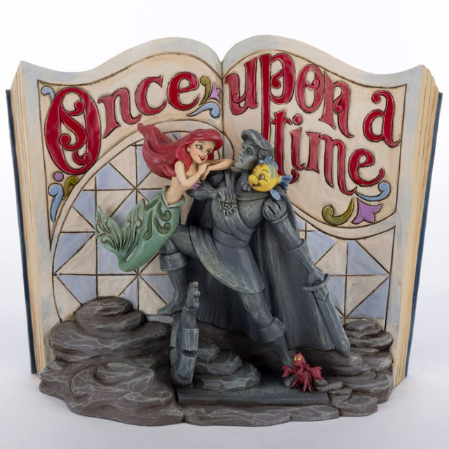 Figurine of Little Mermaid and Prince Eric statue with Sebastian the crab and Flounder against a storybook background
