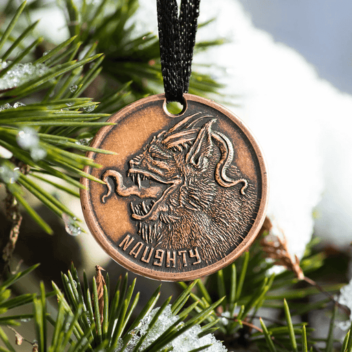 Naughty or Nice Ornament with Krampus on one side, shown hung in a tree