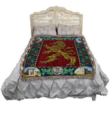 Bed with a decorative blanket featuring a lion emblem on a red background.
