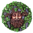 Round decorative wall plaque featuring a classical male face - the god Bacchus - surrounded by green leaves and clusters of purple grapes