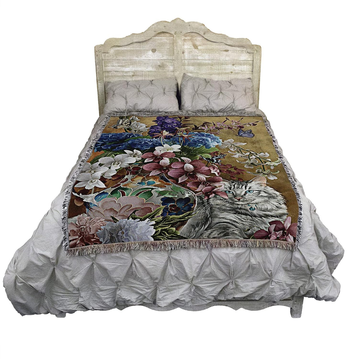 Tapestry blanket with blue eyed gray tabby cat and floral arrangement in a vase with butterflies, shown on a bed