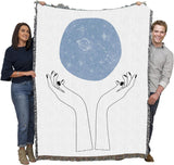 Tapestry blanket showing hands and above them, a blue orb of constellations, held by two adults