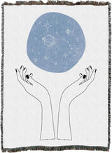 Tapestry blanket showing hands and above them, a blue orb of constellations
