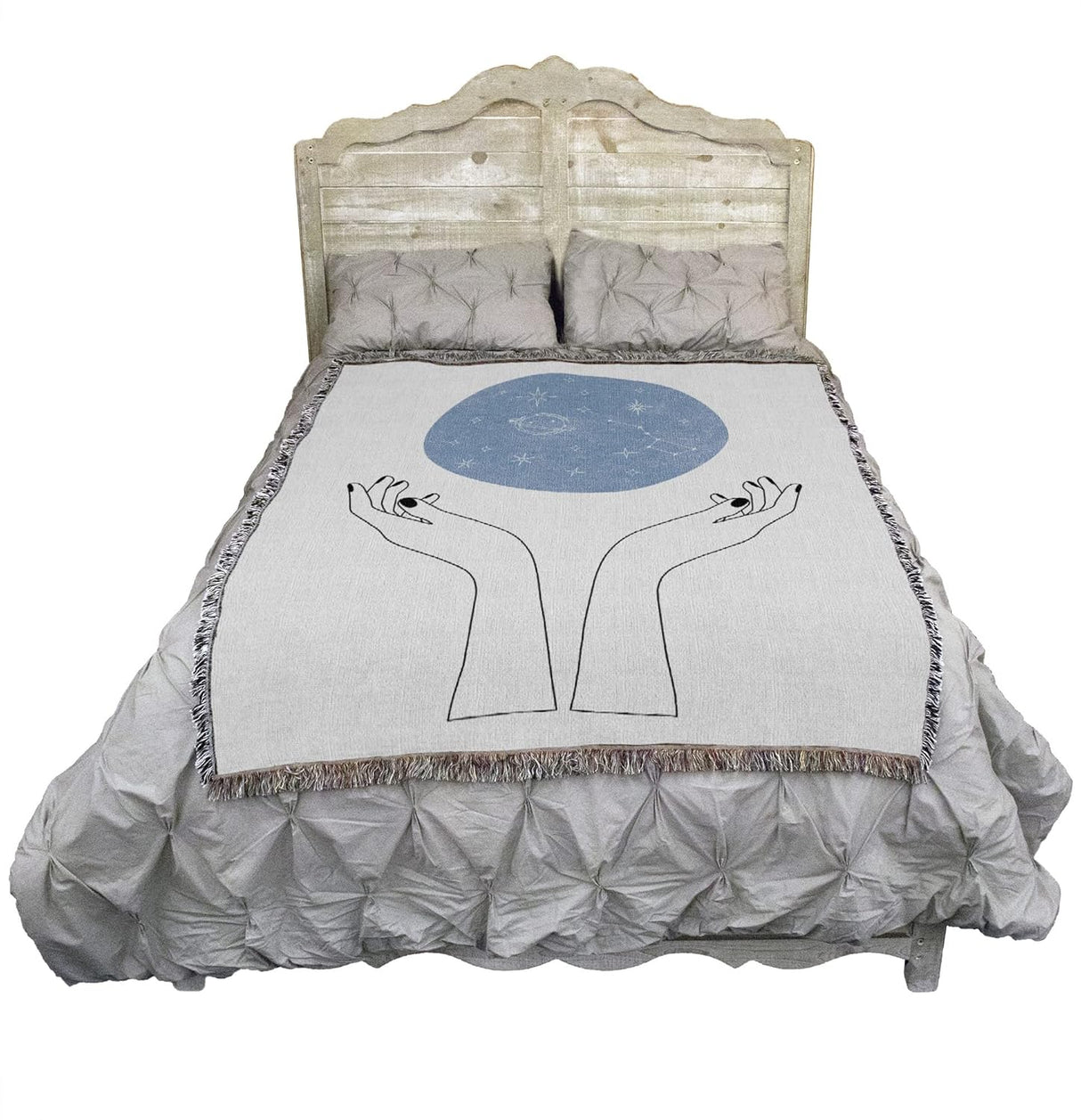 Tapestry blanket showing hands and above them, a blue orb of constellations, on a bed