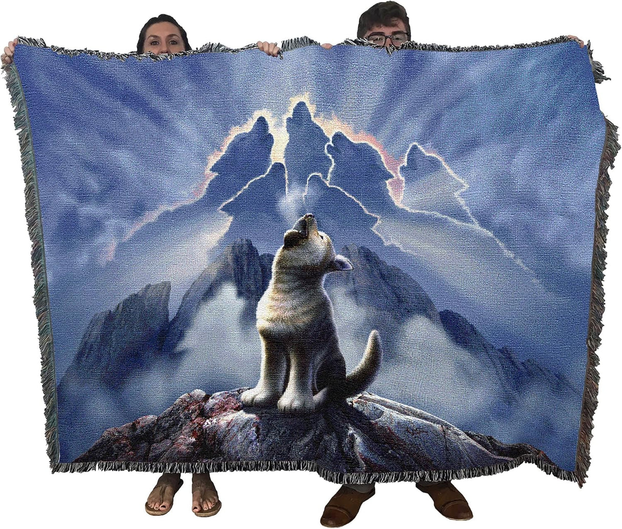Tapestry blanket showing wolf cub howling, more wolves formed of clouds in the sky. Held up by two adults to show blanket's large size