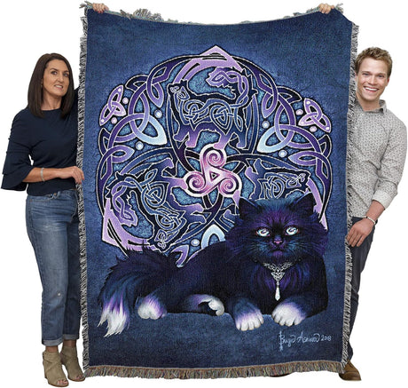 Two people holding a decorative blanket with a cat and Celtic knot design.