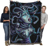 People holding a large blanket with a Medusa design