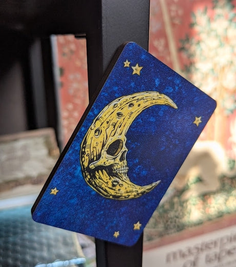 Magnet of a bright yellow skeletal moon and stars on a mottled blue background