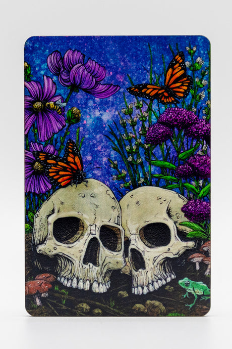 Magnet with two skulls, flowers, and butterflies on a blue background