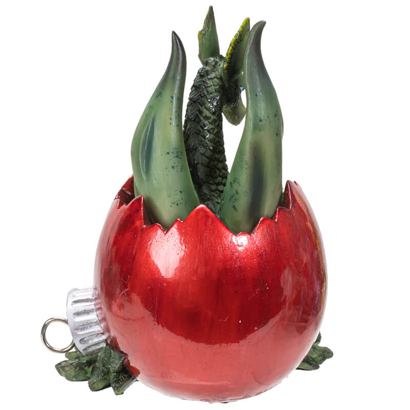 Figurine of a green dragon inside of a red broken Christmas ornament on berries and leaves