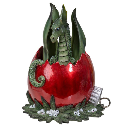 Figurine of a green dragon inside of a red broken Christmas ornament on berries and leaves