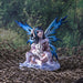 Fairy with blue wings sitting in the snow with a white wolf cub