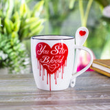White mug with red dripping heart design and spoon, text on mug reads "You Stir my Blood"