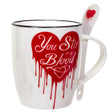 White mug with red dripping heart design and spoon, text on mug reads "You Stir my Blood"
