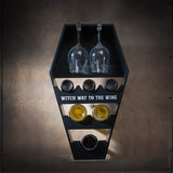 Wine rack in black, coffin shape, with text "Witch way to the wine", shown with wine and glasses