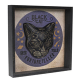 Decorative wall art with a black cat illustration and text on a beige background