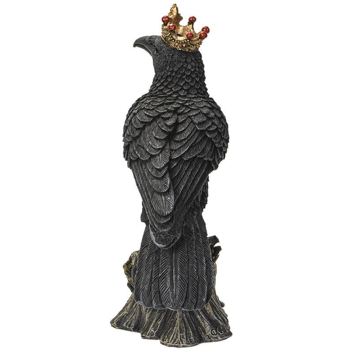 Figurine of a black crow on a branch wearing a golden crown with red accents