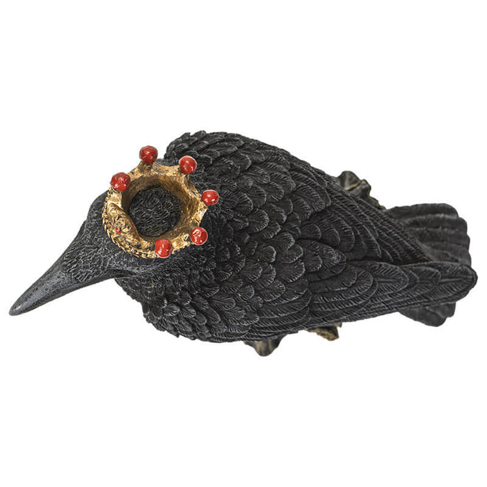 Figurine of a black crow on a branch wearing a golden crown with red accents
