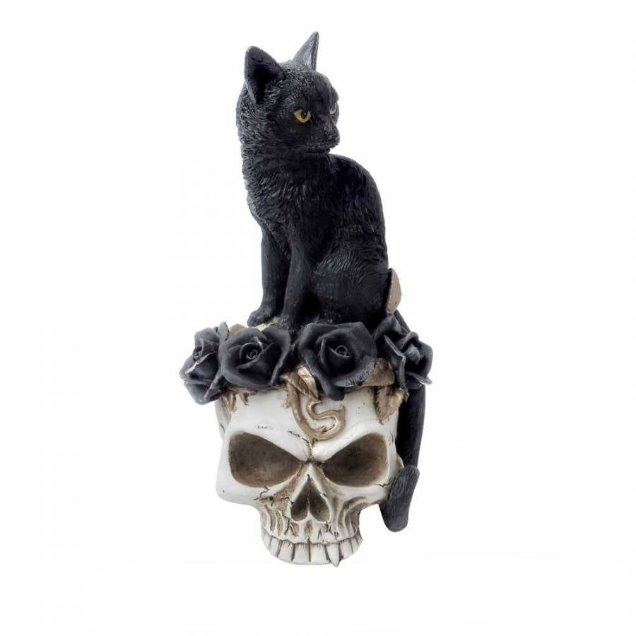 Figurine of black cat sitting on skull adorned with black roses