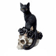 Figurine of black cat sitting on skull adorned with black roses