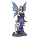 Figurine of fairy in purple dress and wings with crystal ball, perched on a green tree with a white wolf
