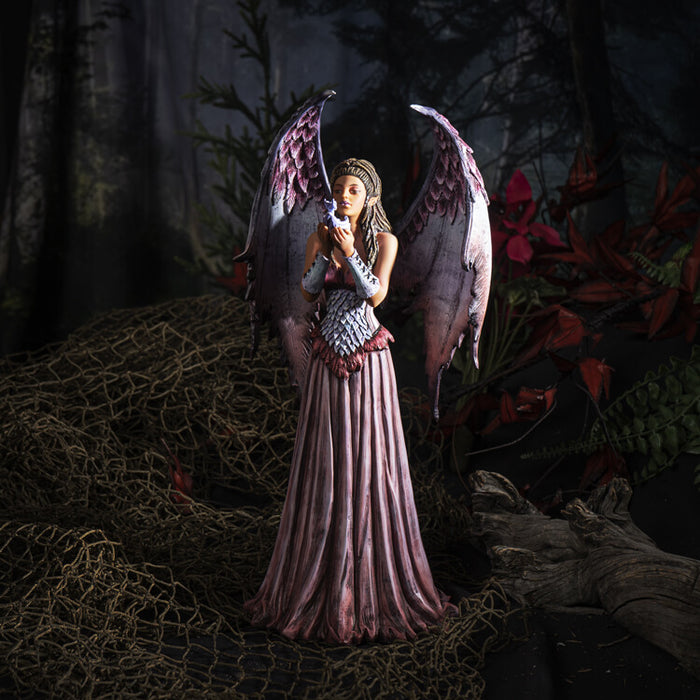 Fairy in pink and baby dragon figurine shown in dark forest setting