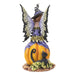 Figurine of a fairy in black and white stripes with purple and green accents sitting on a pumpkin next to a black cat