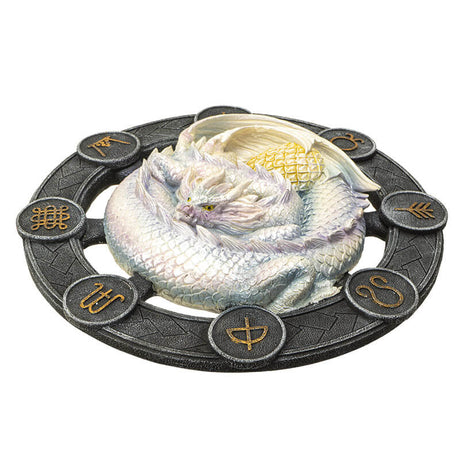 White Ostara dragon on a black wheel with gold symbols