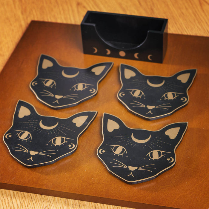 Set of coasters featuring black cat heads with gold accents and moon motif, with matching holder