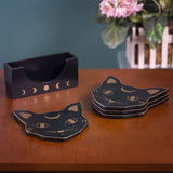 Set of coasters featuring black cat heads with gold accents and moon motif, with matching holder