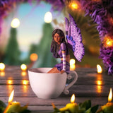 Figurine of a fairy with purple wings and dress and dark skin sitting on the edge of a teacup