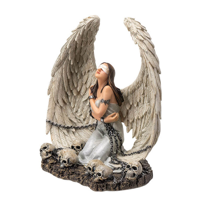 Figurine of a white winged angel woman in chains, blindfolded sitting amongst skulls
