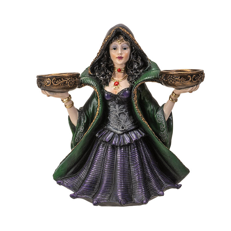 Decorative figurine of a witchy woman in a green cloak and purple dress holding two bowls into which candles can sit