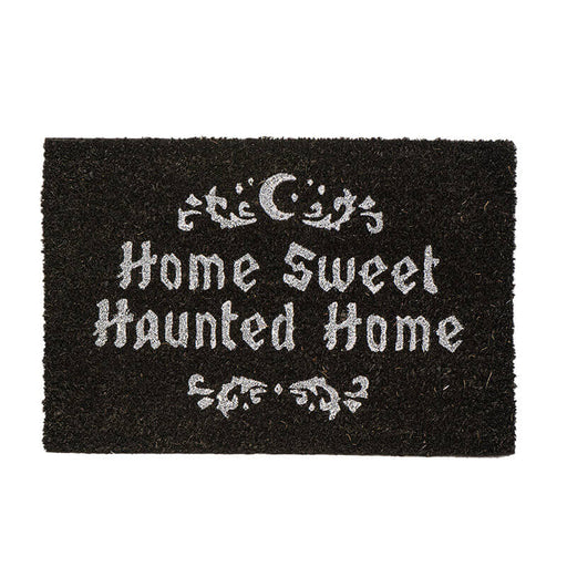 Black doormat with the phrase "Home Sweet Haunted Home" in white, with swirl and moon design above and below