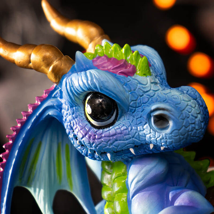 Closeup of dragon face, blue with green and purple accents, gold horns and big eyes