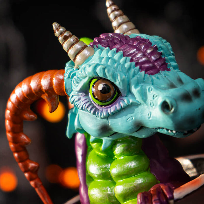 Closeup of blue, purple, green dragon face with big eyes and red horns