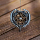 Ornament with two gray dragons framing a heart around a golden pentagram with silver center