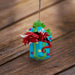 Ornament of red dragon popping out of a blue gift box with yellow and purple stars and green ribbon