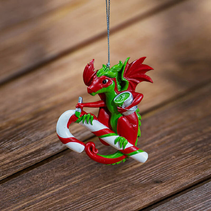 Ornament with red and green dragon painting stripes onto a candy cane