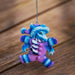 Blue dragon ornament in a purple snow suit with hat and scarf