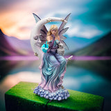 Fairy statue with a crescent moon and owl. Fairy has blue-purple-pink dress and blond hair