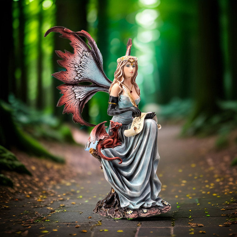 Figurine of a fairy in pale blue dress holding quill and parchment with a small red dragon