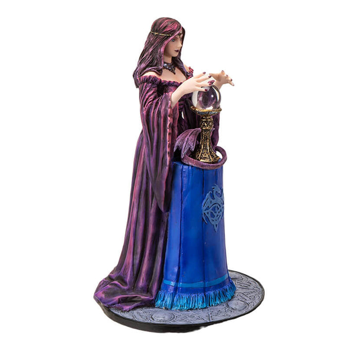 Figurine by Anne Stokes of purple-clad sorceress looking into a crystal ball on a blue table, with a violet dragon curled around the ball's' base