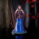 Figurine by Anne Stokes of purple-clad sorceress looking into a crystal ball on a blue table, with a violet dragon curled around the ball's' base