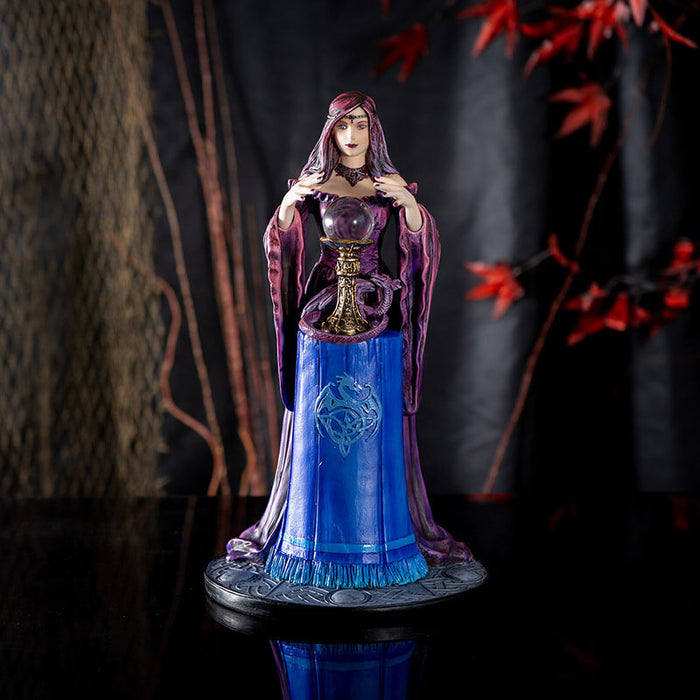 Figurine by Anne Stokes of purple-clad sorceress looking into a crystal ball on a blue table, with a violet dragon curled around the ball's' base