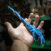 Blue magic wand with a dragon and wave emblem and scales down the length, held in a hand