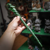 Magic wand in green of dragon spiraling down, holding leaf and mountain coin in mouth